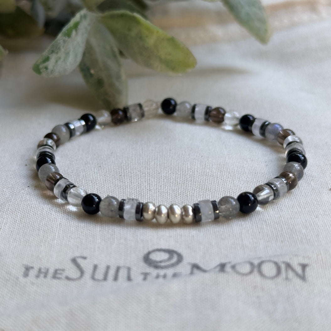 Close-up of a handmade 4mm labradorite and hematite crystal bead bracelet with bright sterling silver accent beads.