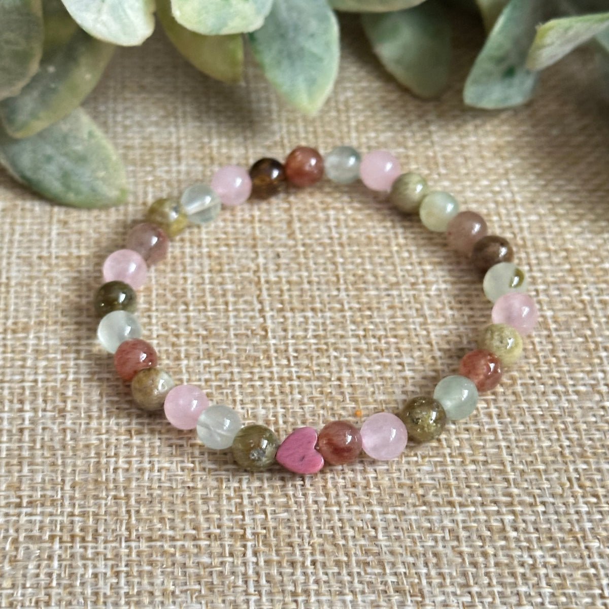 Attracting Love Mini Bracelet featuring Rose Quartz, Strawberry Quartz, Prehnite, and Green Garnet stones that promote joy, self-worth, and divine alignment in love, with an optional silver Evil Eye charm for protection.
