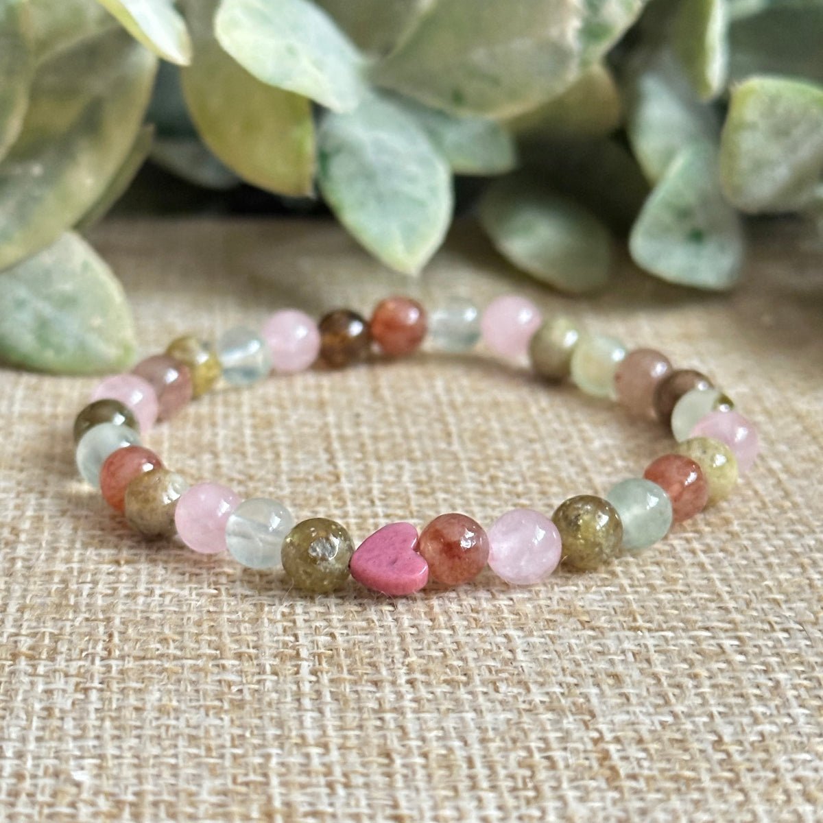 Attracting Love Mini Bracelet with Rose Quartz, heart-shaped Rhodonite, Green Garnet, Strawberry Quartz, Prehnite, and optional silver Evil Eye charm for attracting genuine love and emotional healing.