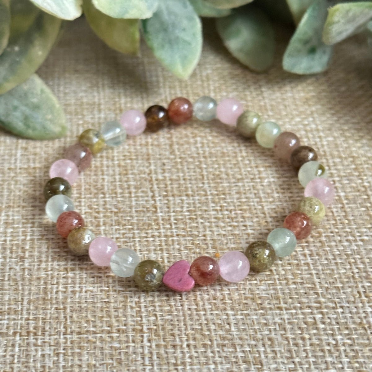 Close-up of Attracting Love Mini Bracelet showing heart-shaped Rhodonite and soft pink Rose Quartz beads symbolizing compassion, forgiveness, and the opening of the heart to new love.