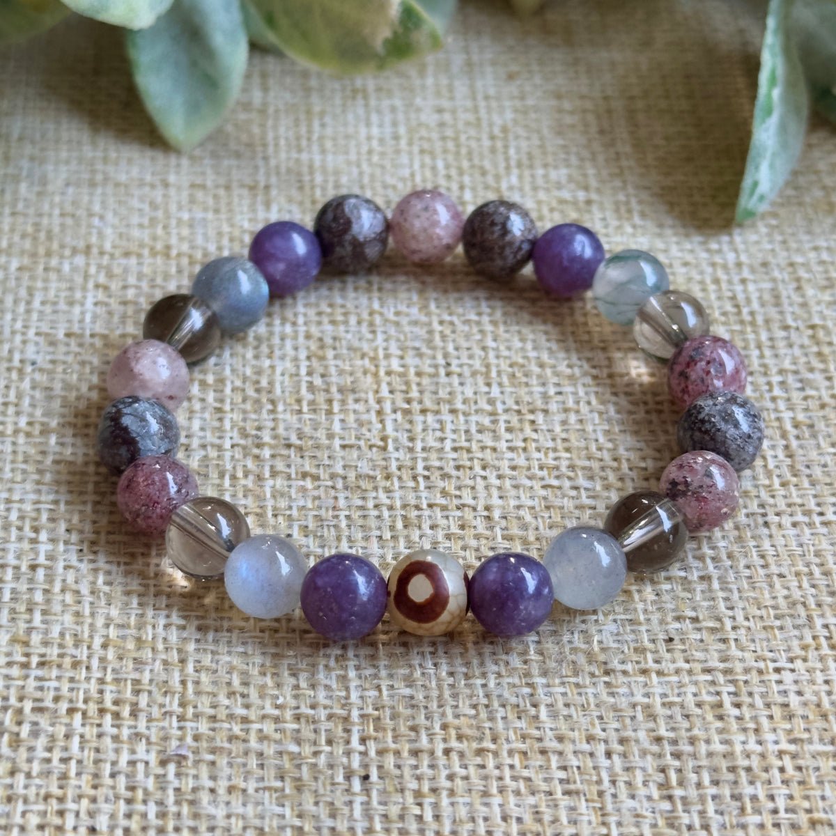 Empath Aura Shield protection bracelet displayed next to its affirmation card and canvas pouch for gifting.