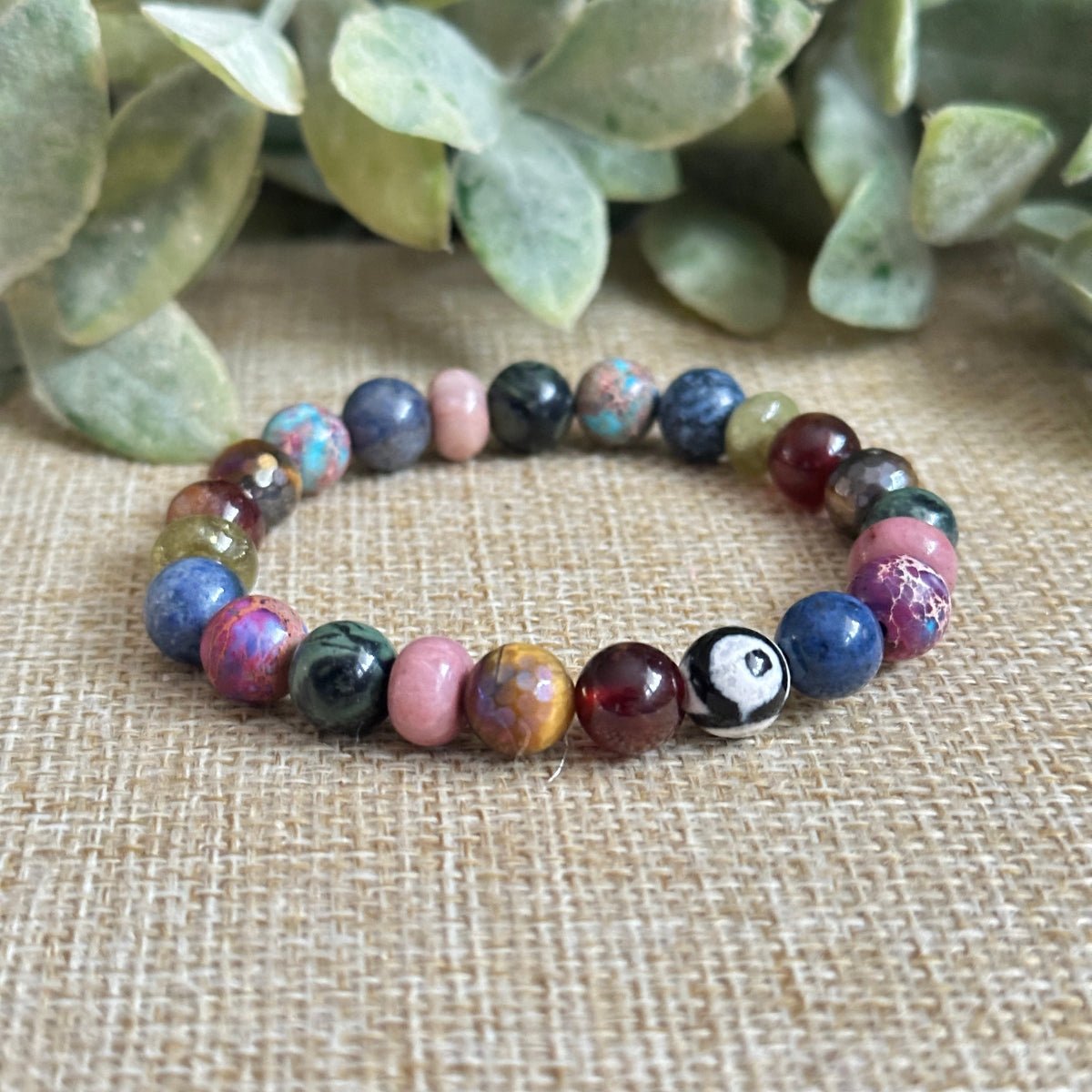 Roots and Wings chakra gemstone bracelet with rich jewel-toned stones symbolizing balance and evolution