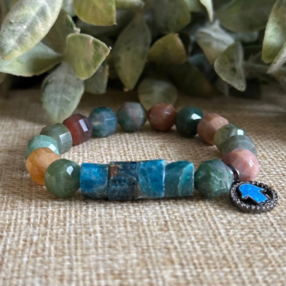With an Open Mind bracelet with blue tones and muted gemstones and opal hamsa pave charm